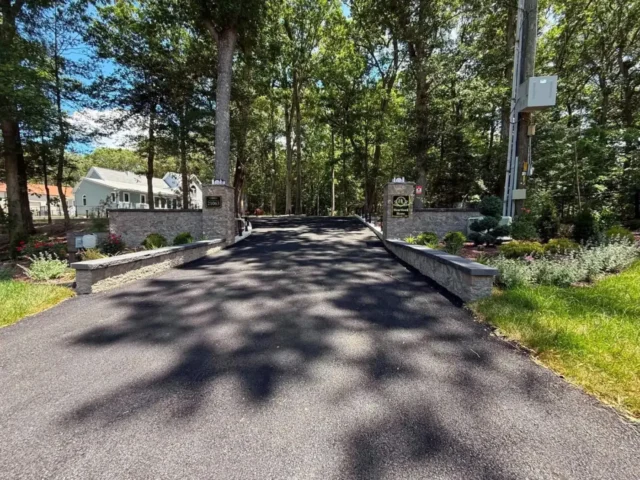New asphalt driveway with stone entrance walls