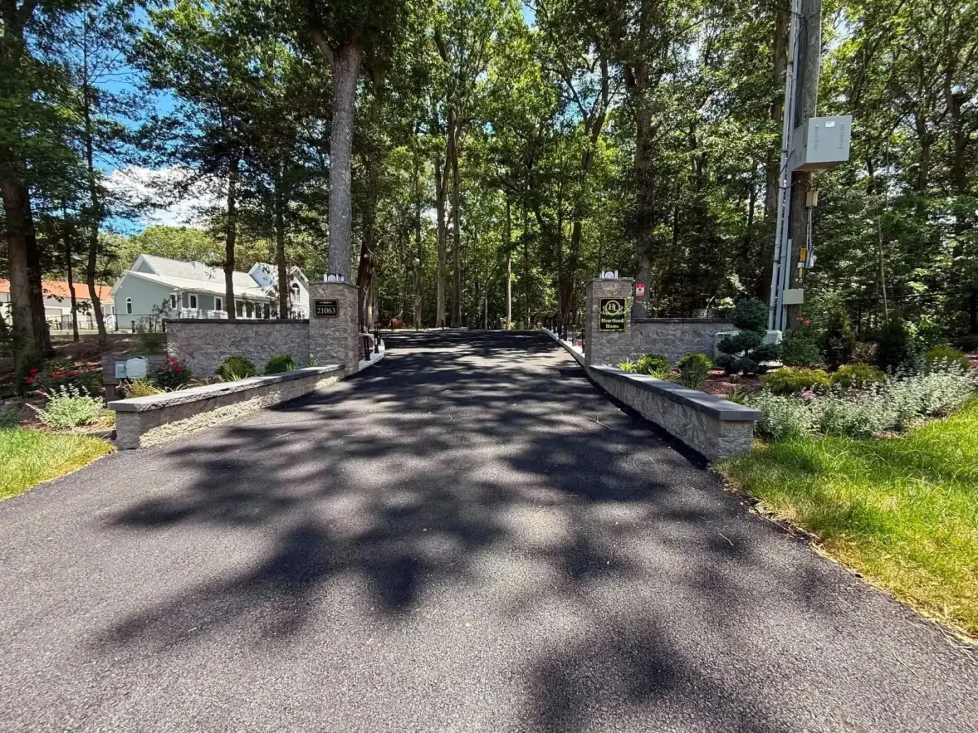 New asphalt driveway with stone entrance walls