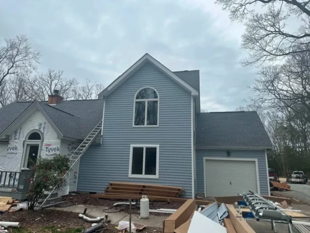 House part-way through new siding, house wrap still showing